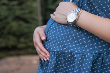 Watch on future mother belly. Outdoor, summer day