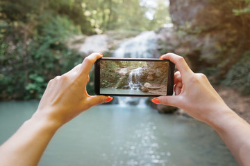 POV of hands taking a photo the waterfall with smartphone. - 298871096