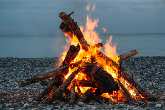 A bonfire on the beach. A bonfire on a stone beach. Fire on the beach - selective focus, copy space. Lonely fire on the seashore