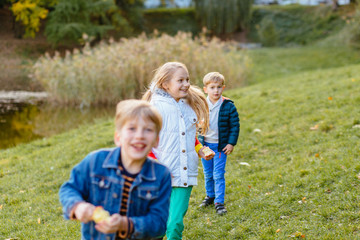 Fototapeta na wymiar Happy kids children boys and girl eating apple fruits outdoor. Brothers with sister on in nature or countyside resting in autumn park. Friendship, relations, happy childhood concept.