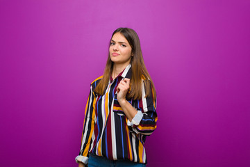 young pretty woman looking arrogant, successful, positive and proud, pointing to self against...