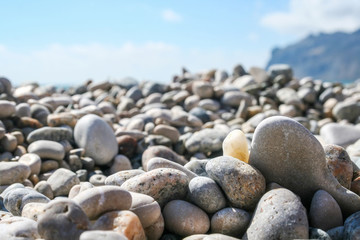 Fototapeta na wymiar Sea pebbles against the blurred mountain and sky
