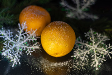 Fototapeta na wymiar Tangerines on a black background. Christmas tree branch. New Year. Copy space. Vegetarianism