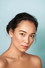Beauty face. Woman with natural makeup and healthy skin portrait. Beautiful asian girl model with fresh glowing hydrated facial skin on blue background at studio closeup. Skin care concept