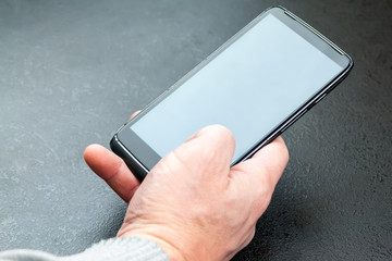 Men's hand with a mobile phone against a gray background