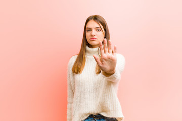 young pretty woman looking serious, stern, displeased and angry showing open palm making stop...