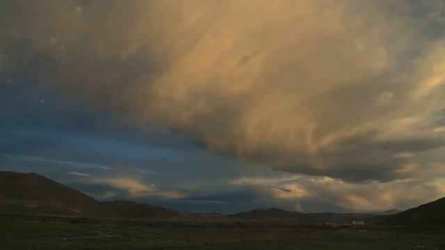 Beautiful wide shot of a big cloud yellow colored timelapse at sunset over a small remote village in the Andes, Bolivia