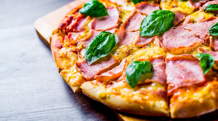 Pizza with Mozzarella cheese, ham, tomato sauce, pepper, Spices and Fresh basil. Italian pizza on wooden table background