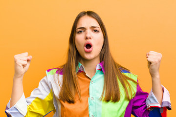 young pretty woman shouting aggressively with an angry expression or with fists clenched...