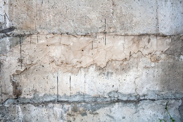 Gray wall covered with an uneven rough layer of plaster with holes, irregularities, cracks and thin traces of flowing black resin