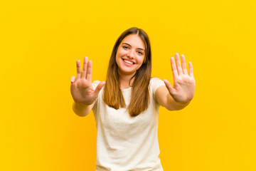 young pretty woman smiling and looking friendly, showing number nine or ninth with hand forward,...