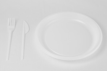 White plastic fork and knife lie to the left of the plate on a white background