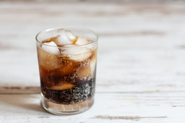 Cold fizzy cola soda with ice cubes in glass.