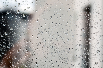 Drops of water on the window glass against a blurred background on a cloudy rainy day