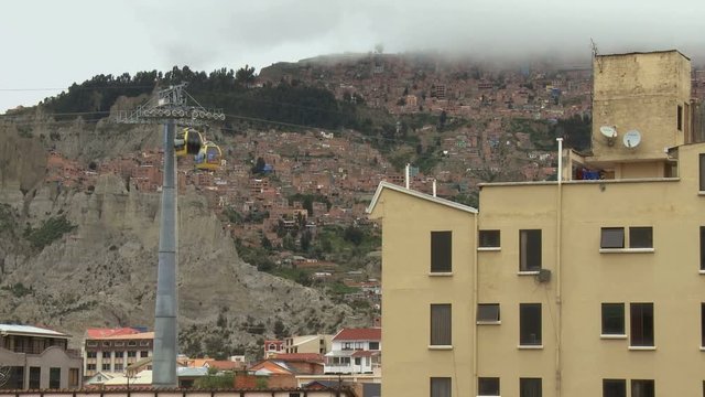Poor hill suburbs view with yellow urban cableway public transport in cloudy day in La Paz, Bolivia