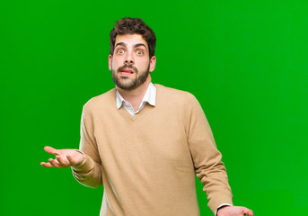 young businessman shrugging with a dumb, crazy, confused, puzzled expression, feeling annoyed and...