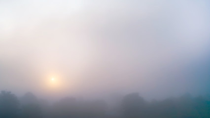 Fototapeta premium Colored sunrise in forested mountain slope with fog ,View from the mountain in the morning, Surat Thani, Thailand.