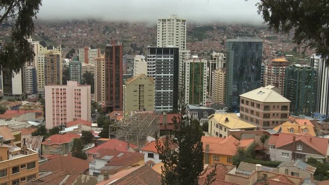 Downtown business district skyscrapers in cloudy day with poor suburbs in the background in La Paz, Bolivia
