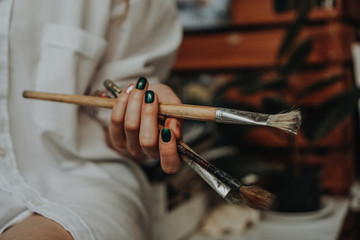 Closeup of female artist hand holding paintbrush at art workshop