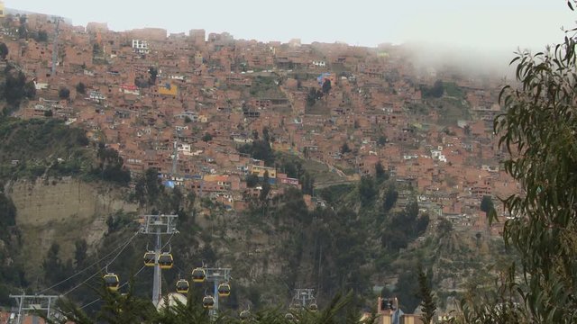 Poor hill suburbs in cloudy day view with yellow public cableway in La Paz, Bolivia