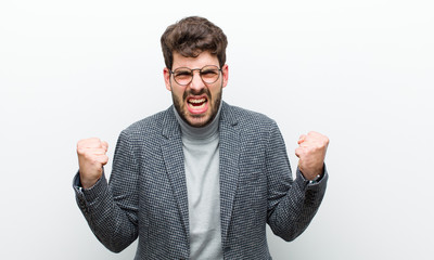 young manager man shouting aggressively with an angry expression or with fists clenched celebrating...