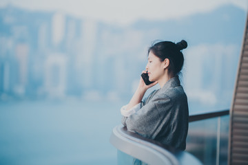 Woman wear bathrobe using smartphone on balcony 