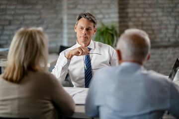 Financial advisor advising senior couple during the meeting in the office.