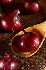 Fresh red onion on kitchen table and wooden spoon