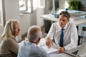 Insurance agent consulting senior couple about  their financial reports on a meeting.