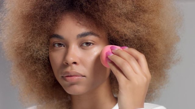 Mixed race black woman with big afro hair makeup herself