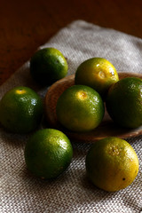 Fresh calamansi on kitchen table and wooden spoon