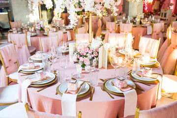 Beautiful dinner table decorated by gold accessories and flowers. Wedding. Decor