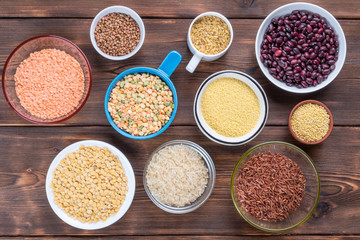 Top view of cereals and grains in bowls on wooden background.