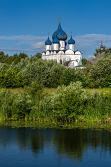 Russia, Vladimir Oblast, Suzdal: Panorama view with famous old White Monument blue onion domed Cathedral of the Nativity of the Theotokos and river Kamenka in one of the oldest Russian towns - travel