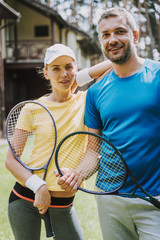 Beautiful couple holding tennis rackets and smiling