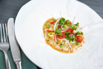 Tartar from scallop with avocado, cherry tomatoes, radishes and onion. Dish in the restaurant from raw seafood.