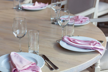 White plates with pink napkins on a wooden table