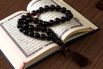 black rosaries lie on the pages of an open Quran