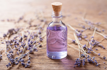 Glass bottle of lavender essential oil with dried lavender flowers