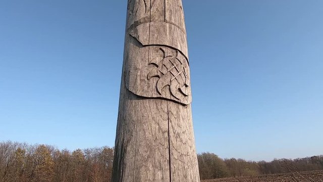 Wooden idol Slavic god Svarog on a background of blue sky