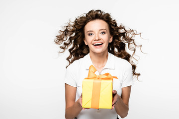 attractive curly girl holding yellow gift box, isolated on white