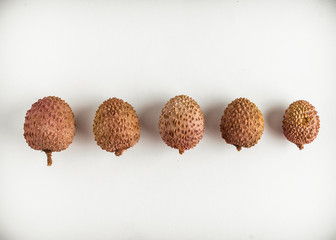  Lychee fruits lie in a row on a white background