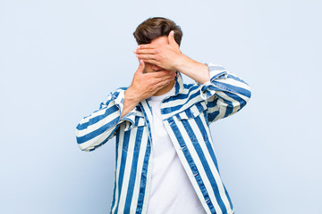 young handsome man covering face with both hands saying no to the camera! refusing pictures or...