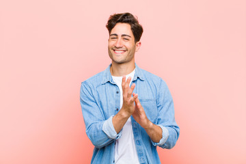young handsome man feeling happy and successful, smiling and clapping hands, saying congratulations...
