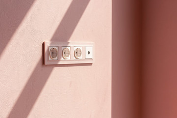 White electrical outlet in the room on a pink background