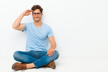 young handsome man greeting the camera with a military salute in an act of honor and patriotism,...