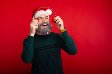 Cheerful man listening music over red background