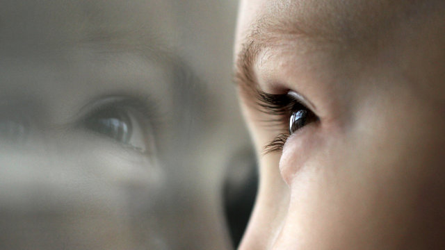 Little boy looking through window. Eye macro. Reflection of the face in the glass.