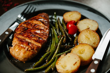 Steak with fried potatoes and green beans in a white plate
