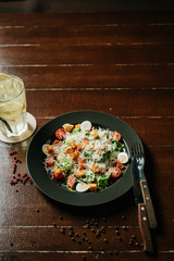 Fresh caesar salad in white plate on dark wooden table. Top view copy space.